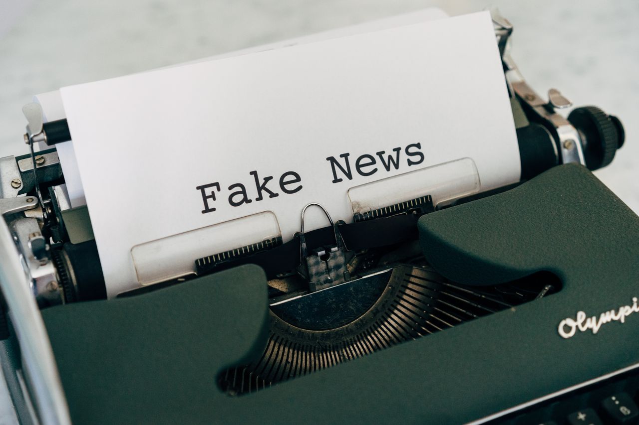 Close-up of vintage typewriter printing Fake News, depicting false information concepts.